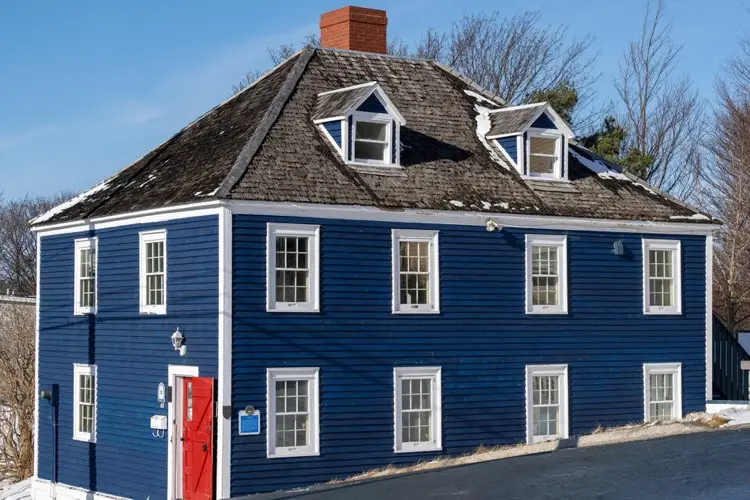 Blue sided house with red door and hip roof