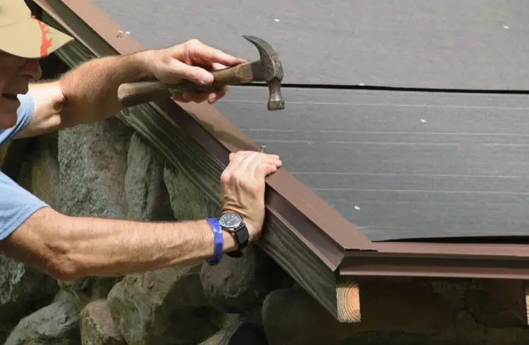 Drip edge flashing being installed by a man and a hammer