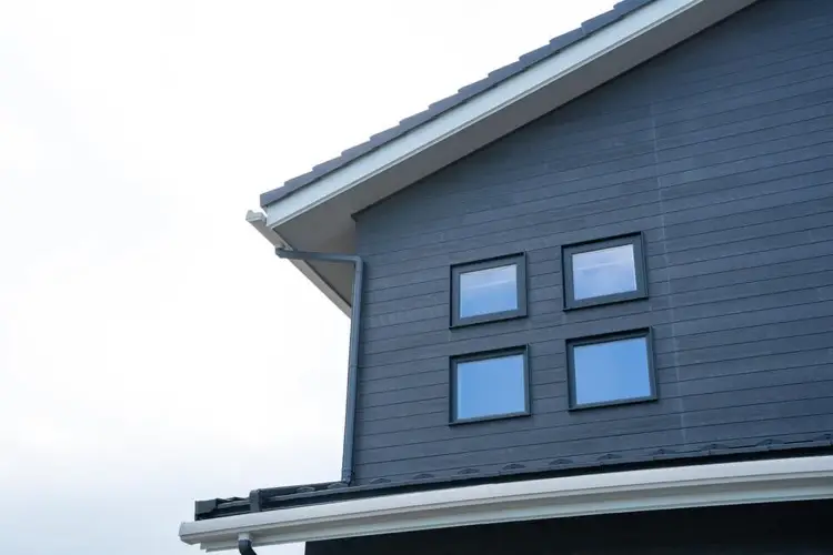 Dark gray sided house with eave overhangs