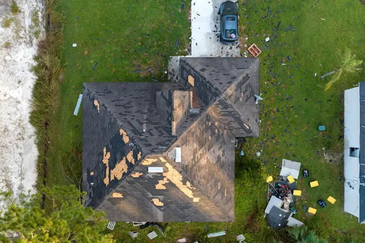Aerial view of storm-damaged shingle roof with missing shingles