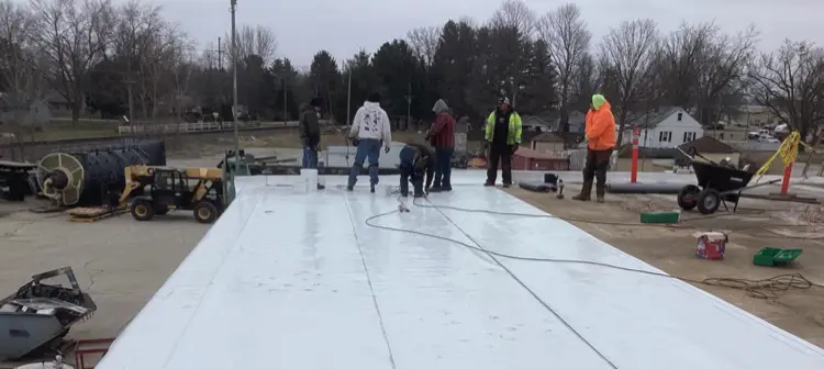 Commercial roofing crew installing membrane on a flat roof