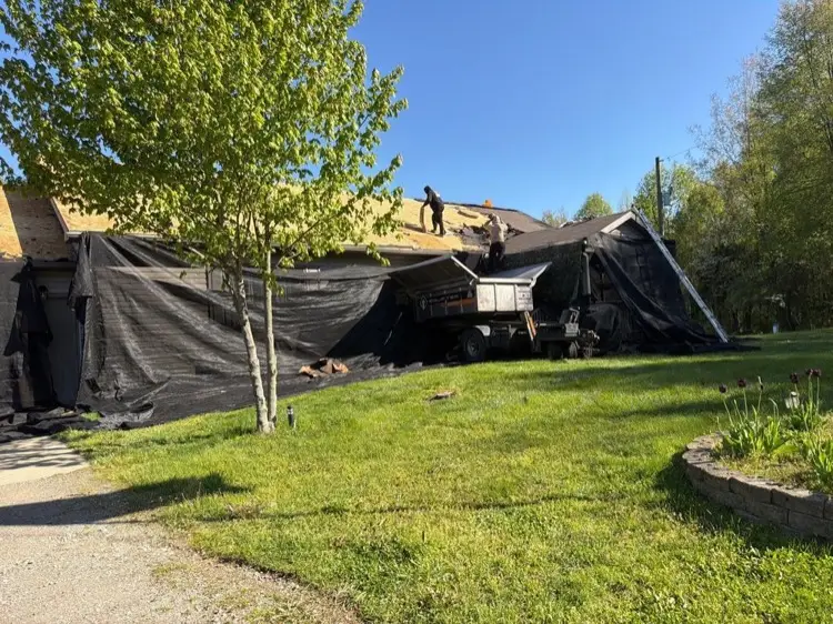 Better Way crew tearing off a roof in Jones Michigan with the house fully wrapped in protective catch-all netting