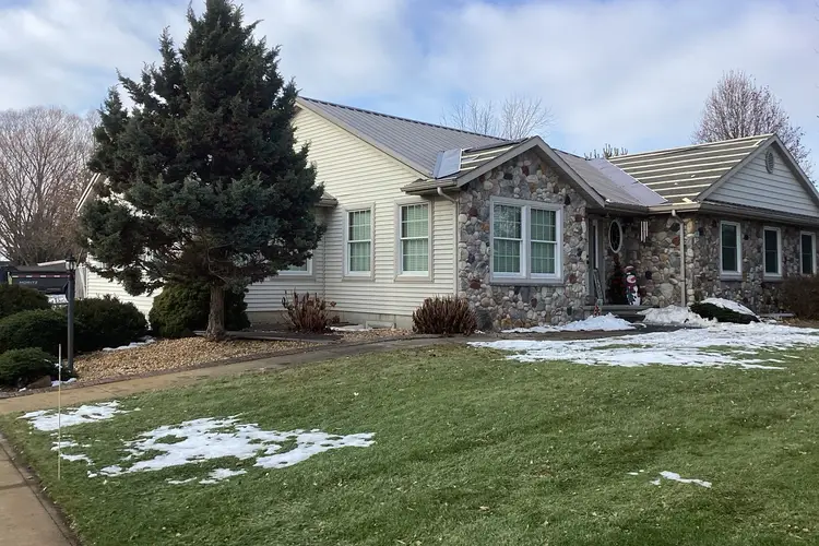 Burnished slate exposed fastener metal roof on a stone and vinyl ranch home in Goshen Indiana, installed by Better Way Roofing