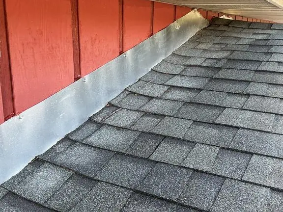 Metal wall flashing running along the joint between asphalt shingles and siding on a Niles Michigan roof