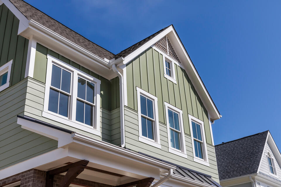 green sided house with white trim and shingle roof