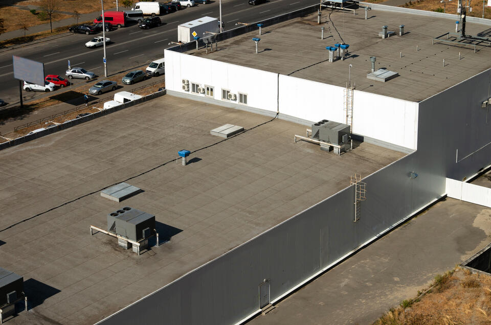 distant view of multilevel commercial roof with various ventilation and hvac appliances on surface of roof