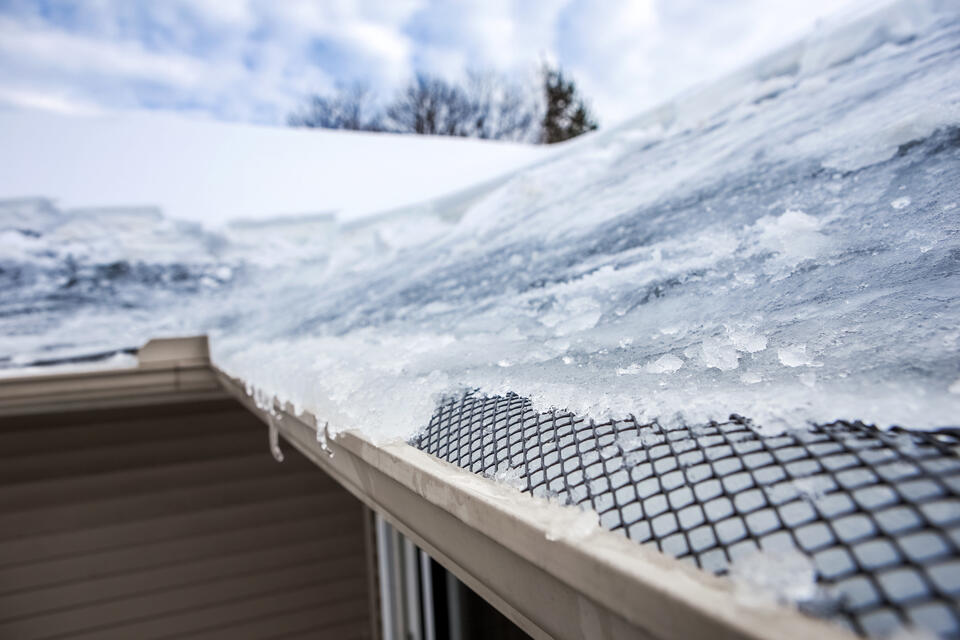 how to prevent ice dams on roof-close up of ice collecting on roof and around gutters